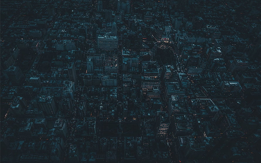 Aerial View of a Dark City at Night with Scattered Lights and Deep Blue Tones HD wallpaper