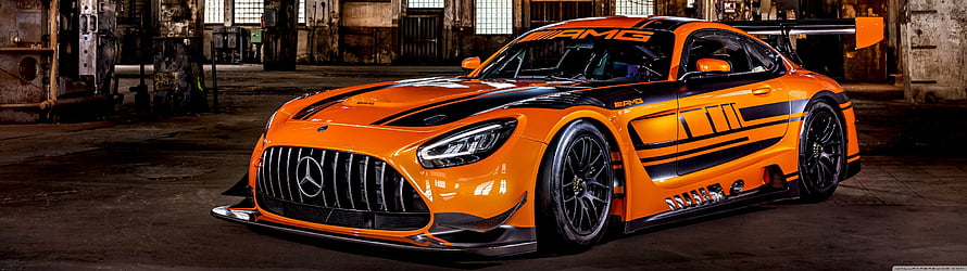 Orange Mercedes-AMG GT3 Race Car with Black Racing Livery in Industrial Warehouse Setting HD wallpaper