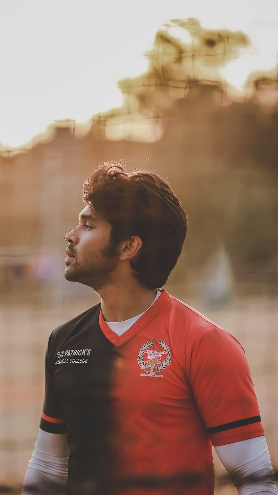 Dhruv Vikram in red and black sports jersey with golden hour backlight HD phone wallpaper