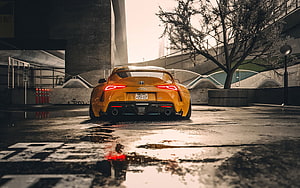 Rear View of a Modified Orange Toyota Supra Parked on a Wet Urban Street HD wallpaper