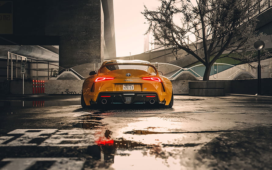Rear View of a Modified Orange Toyota Supra Parked on a Wet Urban Street HD wallpaper