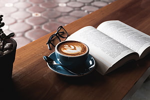 Cozy Cafe Scene With Latte Art, Open Book, And Reading Glasses On A Wooden Table HD wallpaper