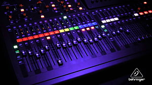 Illuminated Behringer Audio Mixing Console with Colorful Faders and Buttons in a Dark Studio Setting HD wallpaper