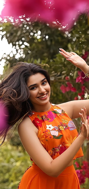Krithi Shetty in Vibrant Orange Floral Dress Amidst Lush Garden Blooms HD phone wallpaper