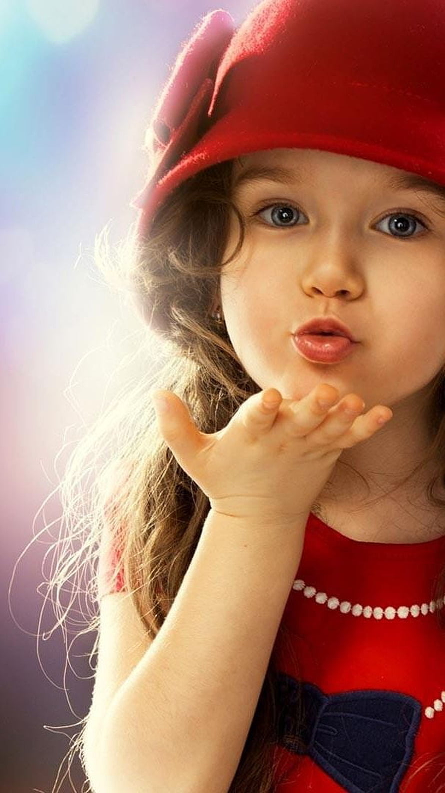 Cute little girl in a red hat blowing a kiss with soft backlight and warm tones HD phone wallpaper