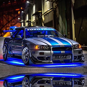 Nissan Skyline R34 GT-R with Blue Underglow and Racing Stripes in Night Street Scene HD phone wallpaper