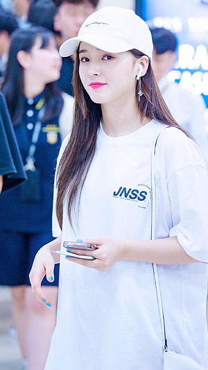 Nancy from Momoland in a white cap and oversized t-shirt at an airport HD phone wallpaper