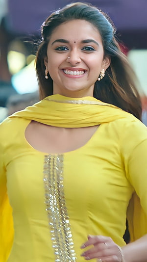 Keerthi Suresh in a bright yellow traditional outfit with gold sequin detailing and a warm smile HD phone wallpaper