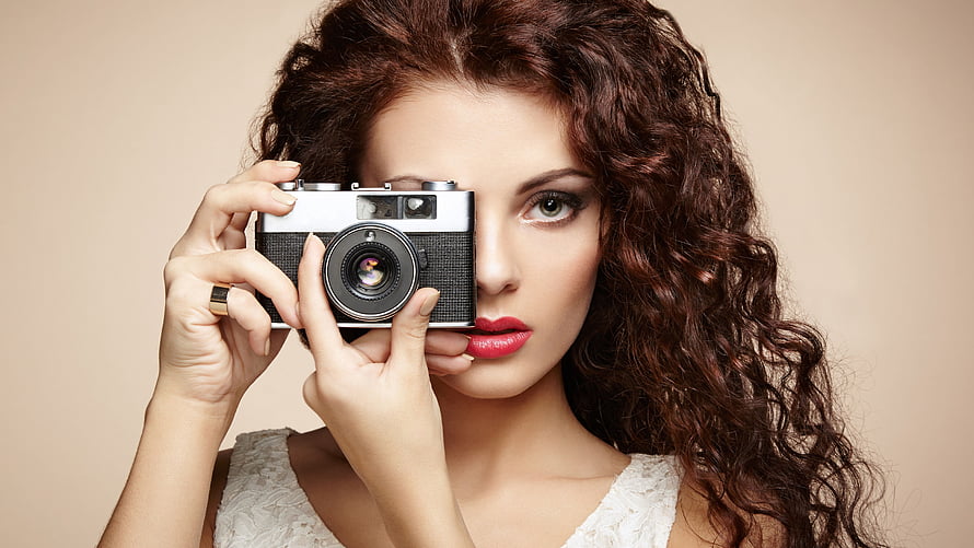 Curly Haired Woman Holding Vintage Rangefinder Camera in Studio Portrait HD wallpaper