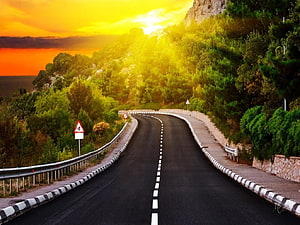 Winding Mountain Road at Golden Hour with Vibrant Sunset Sky and Lush Greenery HD wallpaper
