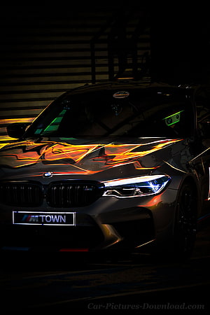 BMW M5 CS Front End with Dramatic Orange Light Reflections in Dark Setting HD phone wallpaper