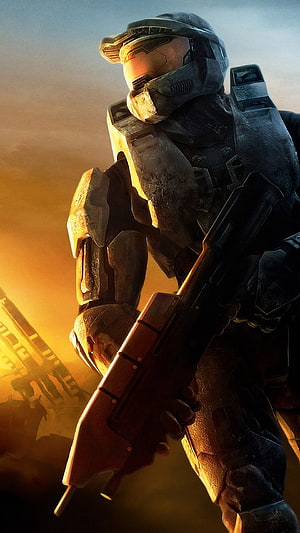 Master Chief in battle-worn armor holding a rifle against a golden sunset backdrop HD phone wallpaper