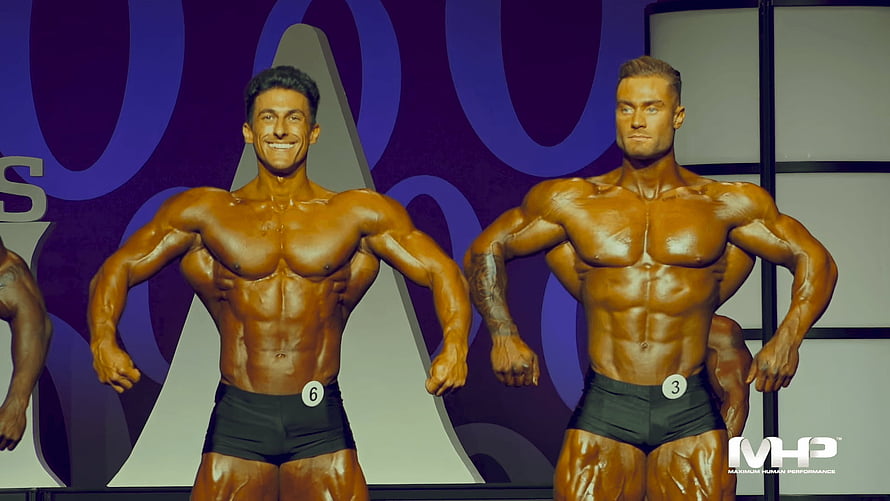 Chris Bumstead and bodybuilder rival posing on stage at MHP competition HD wallpaper