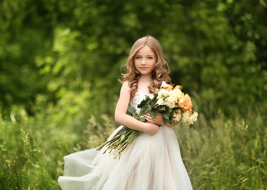 Young girl in white tulle dress holding a bouquet of flowers in a green meadow HD wallpaper