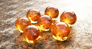Dragon Ball Z Crystal Orbs with Red Stars on Rustic Wooden Surface HD wallpaper