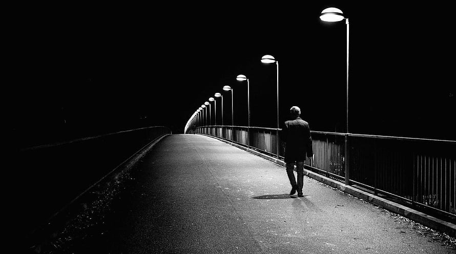 Solitary figure walking along a dark bridge at night under a row of streetlights HD wallpaper