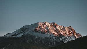 Snow-Capped Mountain Peak Bathed in Golden Sunset Light Against a Clear Sky HD wallpaper