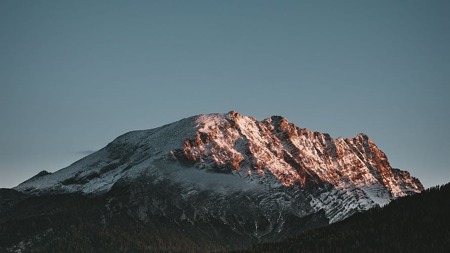 Snow-Capped Mountain Peak Bathed in Golden Sunset Light Against a Clear Sky HD wallpaper