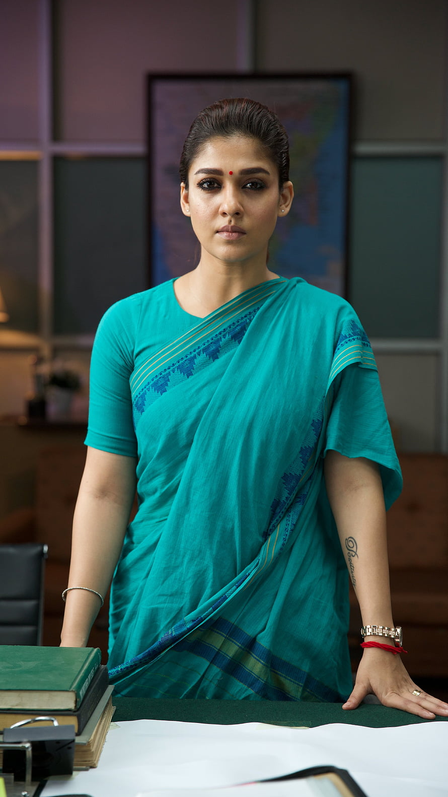 Nayanthara in a teal saree standing at a desk in a professional office setting HD phone wallpaper