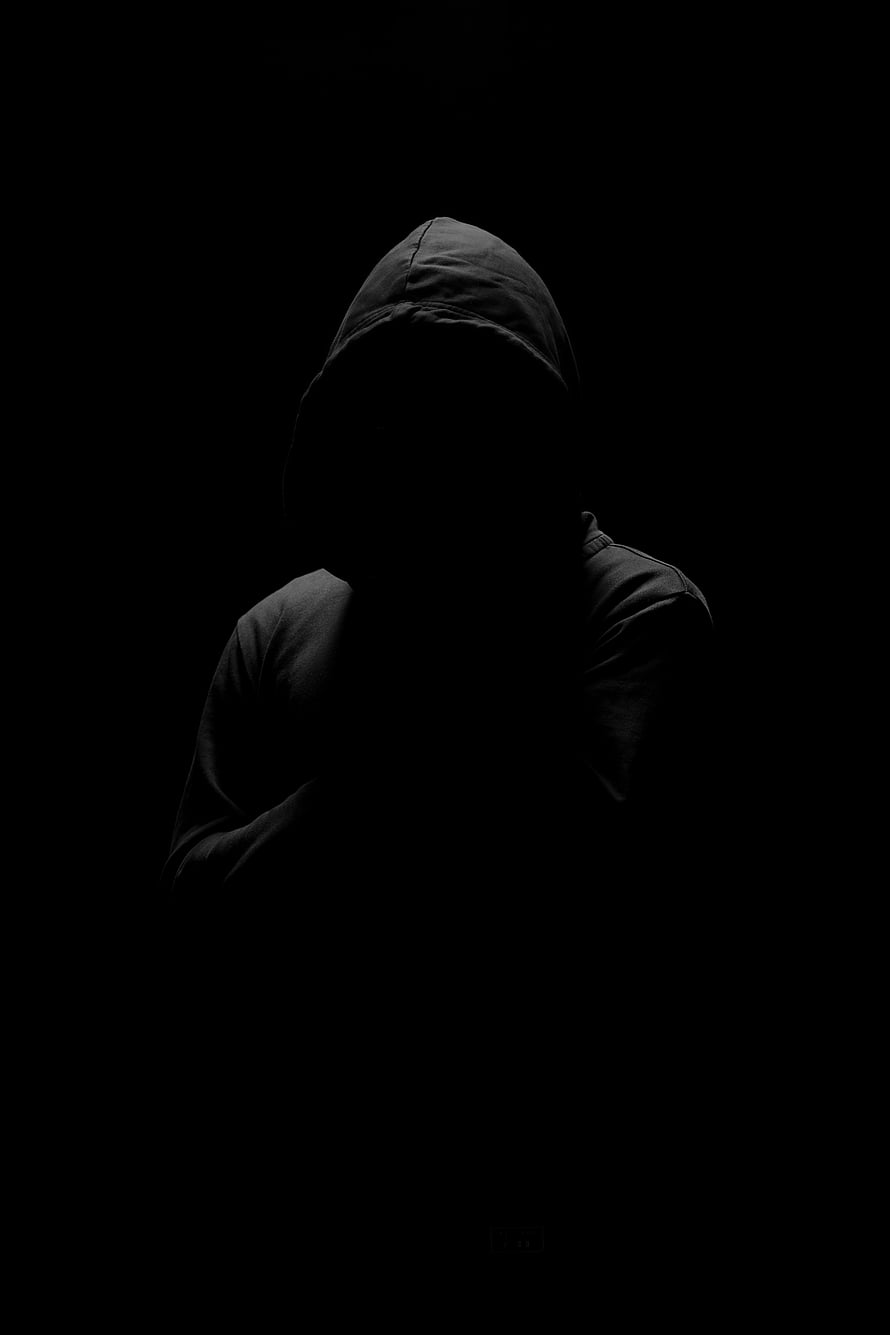 Silhouette of a person in a dark hooded sweatshirt against a black background HD phone wallpaper