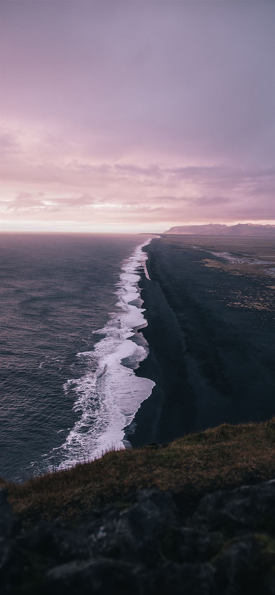 Aerial View of Iceland's Black Sand Beach at Dusk with Purple Sky and Distant Mountains HD phone wallpaper