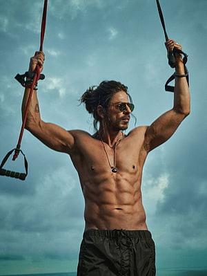 Shah Rukh Khan performing outdoor suspension training against a dramatic cloudy sky HD phone wallpaper