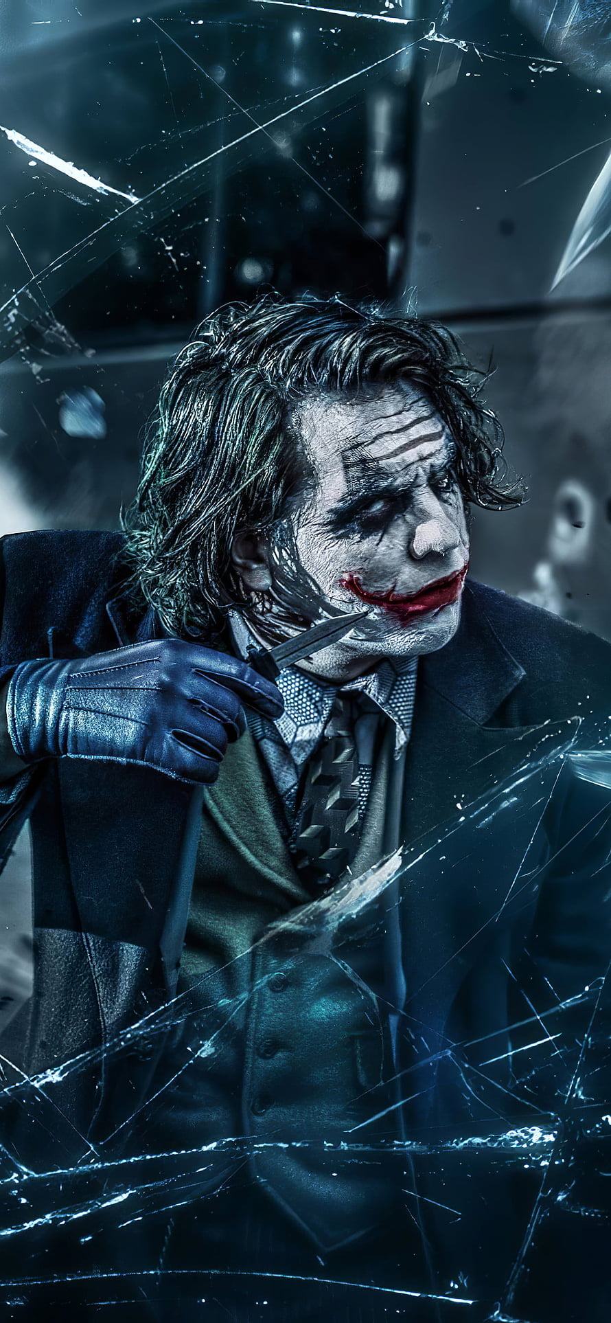 Joker holding a knife through shattered glass in a dark cinematic portrait HD phone wallpaper