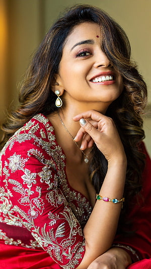 Shreya Saran in a red embroidered lehenga with gold jewelry and a warm smile HD phone wallpaper
