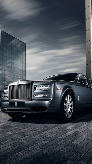 Rolls Royce Ghost luxury sedan parked on dark stone pavement under dramatic overcast sky HD phone wallpaper