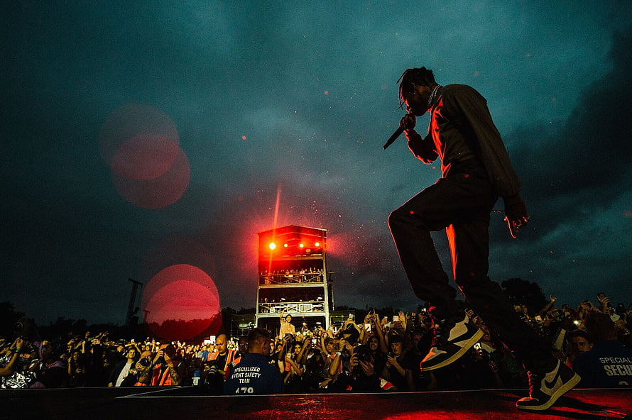Travis Scott performing live on stage at a night concert with dramatic red lighting and a large crowd HD wallpaper