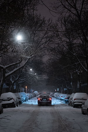 Snow-Covered City Street at Night with Parked Cars and Glowing Streetlights HD phone wallpaper