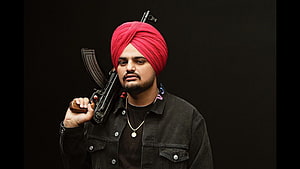 Sidhu Moose Wala Portrait in Red Turban with Rifle Against Black Background HD wallpaper