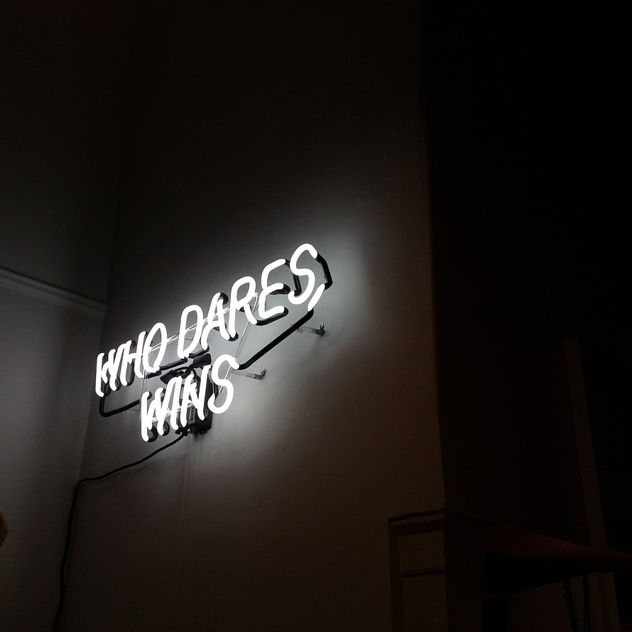 Glowing White Neon Sign Reading Who Dares Wins on a Dark Interior Wall HD phone wallpaper