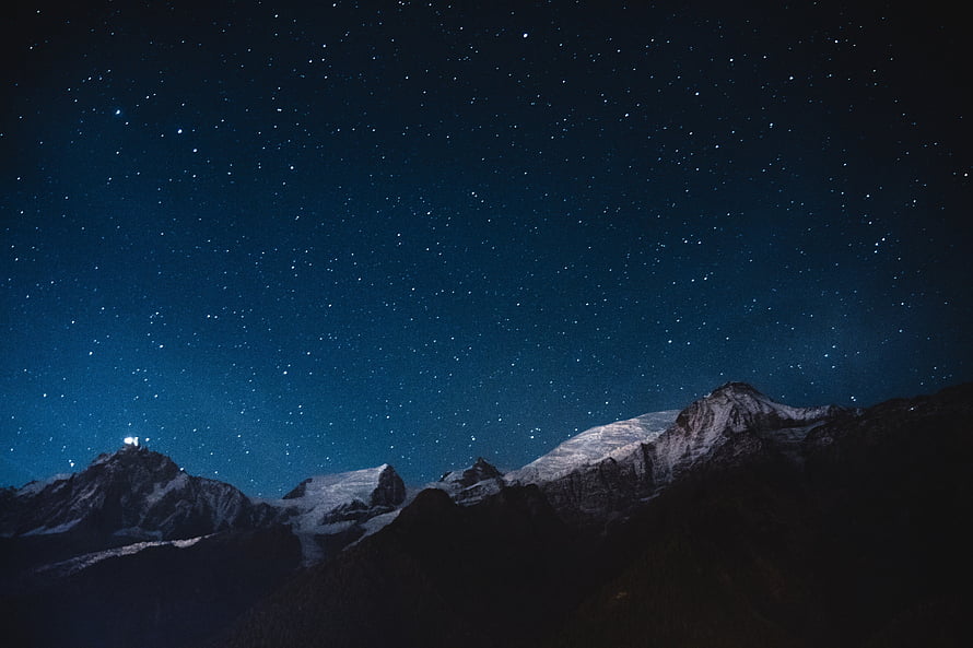 Snow-Capped Mountain Ranges Under a Deep Blue Starry Night Sky HD wallpaper