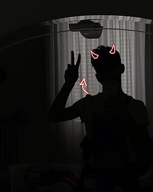Silhouette of a person making a peace sign with glowing red devil horns and arrow overlay in a dark room HD phone wallpaper