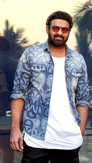 Prabhas in a patterned denim shirt and sunglasses with a confident outdoor pose HD phone wallpaper