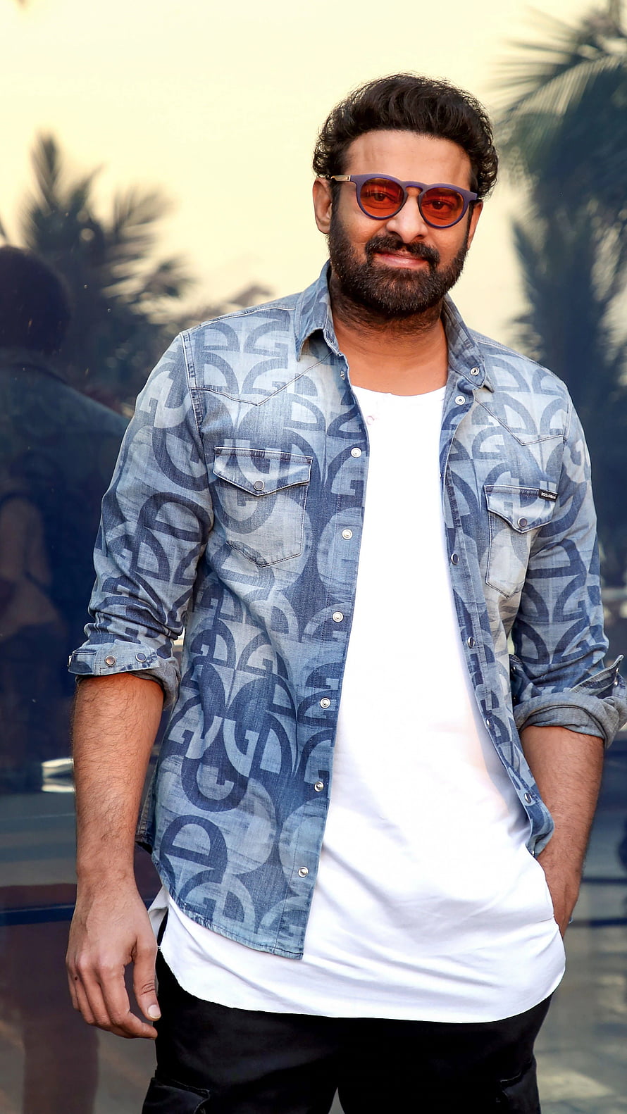 Prabhas in a patterned denim shirt and sunglasses with a confident outdoor pose HD phone wallpaper