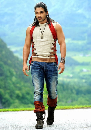 Allu Arjun in rustic warrior costume walking on a mountain road with green hills in the background HD phone wallpaper