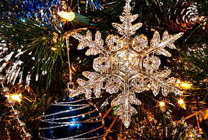 Crystal Snowflake Ornament on a Festive Christmas Tree with Warm Lights and Pine Cones HD wallpaper