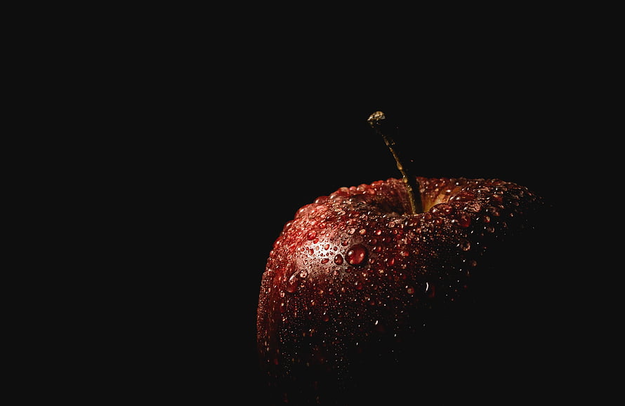 Glossy red apple covered in water droplets against a dark black background HD wallpaper