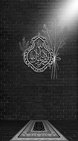 Elegant Islamic Calligraphy Art on Dark Brick Wall with Prayer Rug and Floral Accents HD phone wallpaper