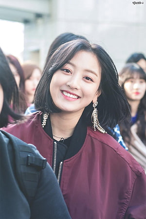 Jihyo from TWICE smiling in a maroon bomber jacket with statement earrings HD phone wallpaper
