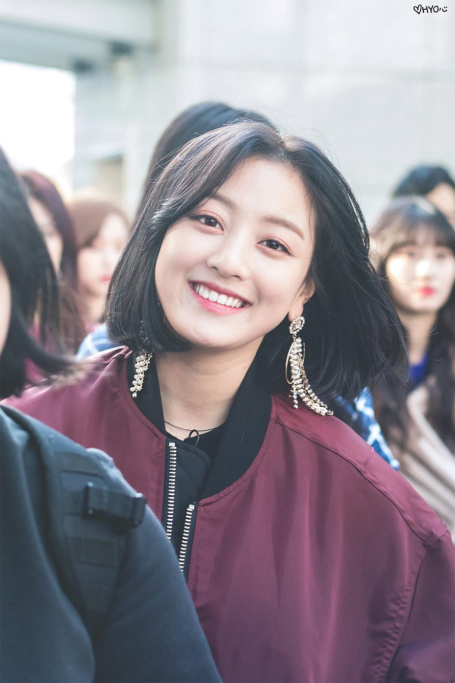 Jihyo from TWICE smiling in a maroon bomber jacket with statement earrings HD phone wallpaper