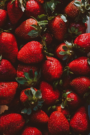 Vibrant Close-Up of Fresh Ripe Strawberries with Green Leaves HD phone wallpaper