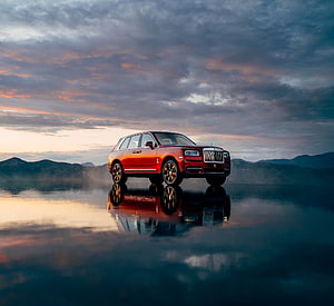 Red Rolls-Royce Cullinan SUV Parked on Reflective Water at Sunset HD wallpaper