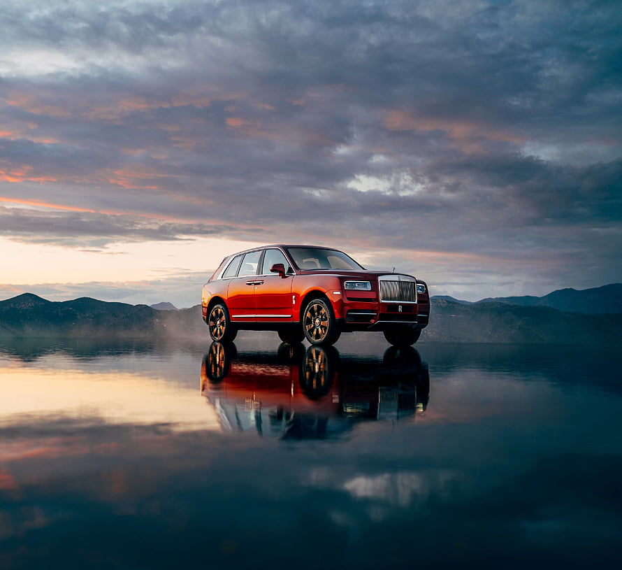 Red Rolls-Royce Cullinan SUV Parked on Reflective Water at Sunset HD wallpaper