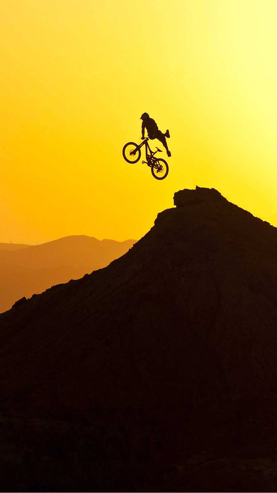Mountain Biker Silhouette Launching Off a Rocky Ridge at Golden Hour HD phone wallpaper