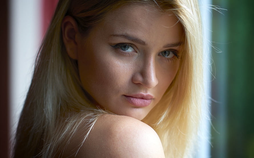 Close-up portrait of a blonde woman with blue eyes looking over her shoulder HD wallpaper