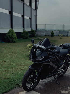 Black Yamaha R15 V4 Sportbike Parked on Grass with Modern Building Background HD phone wallpaper