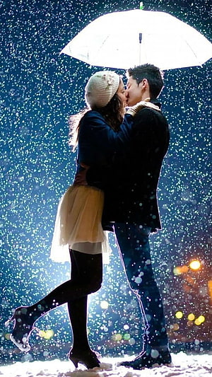 Romantic couple sharing a kiss under a white umbrella in falling snow at night HD phone wallpaper